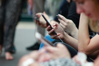Vierekkäin istuvat ihmiset selaavat puhelimiaan